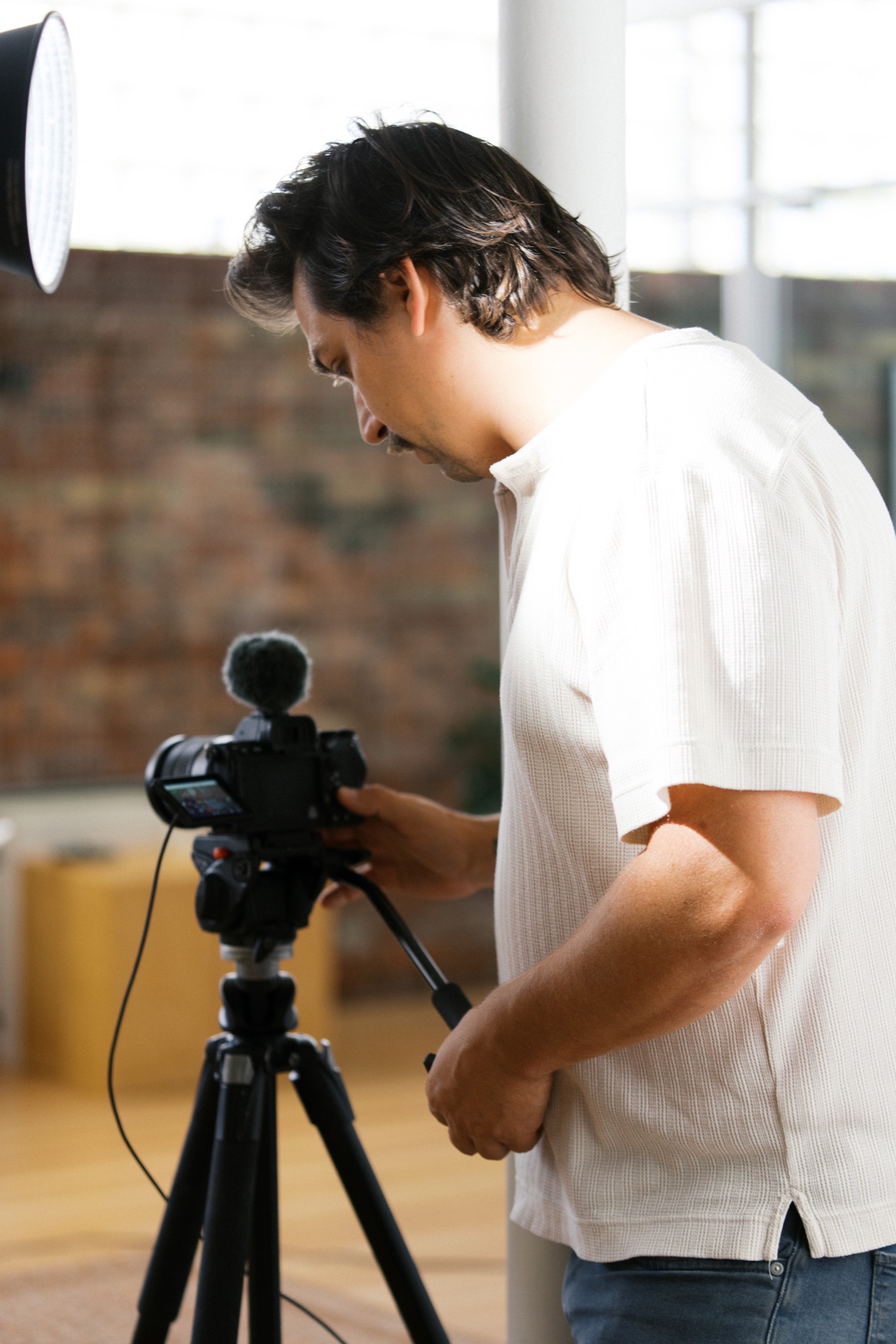 A videographer adjusting a camera and microphone on a tripod