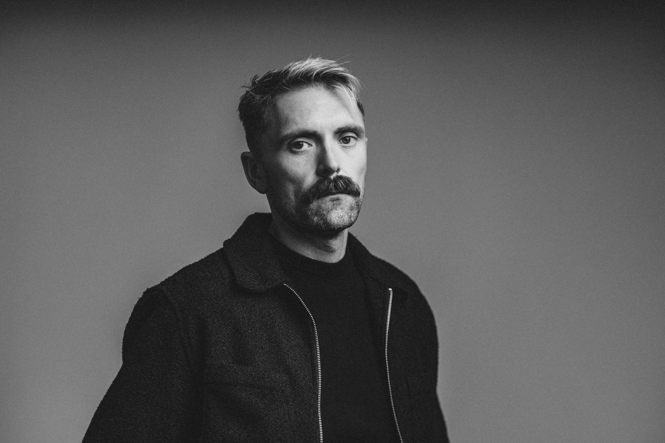 Black-and-white portrait of Jordon in a dark jacket.