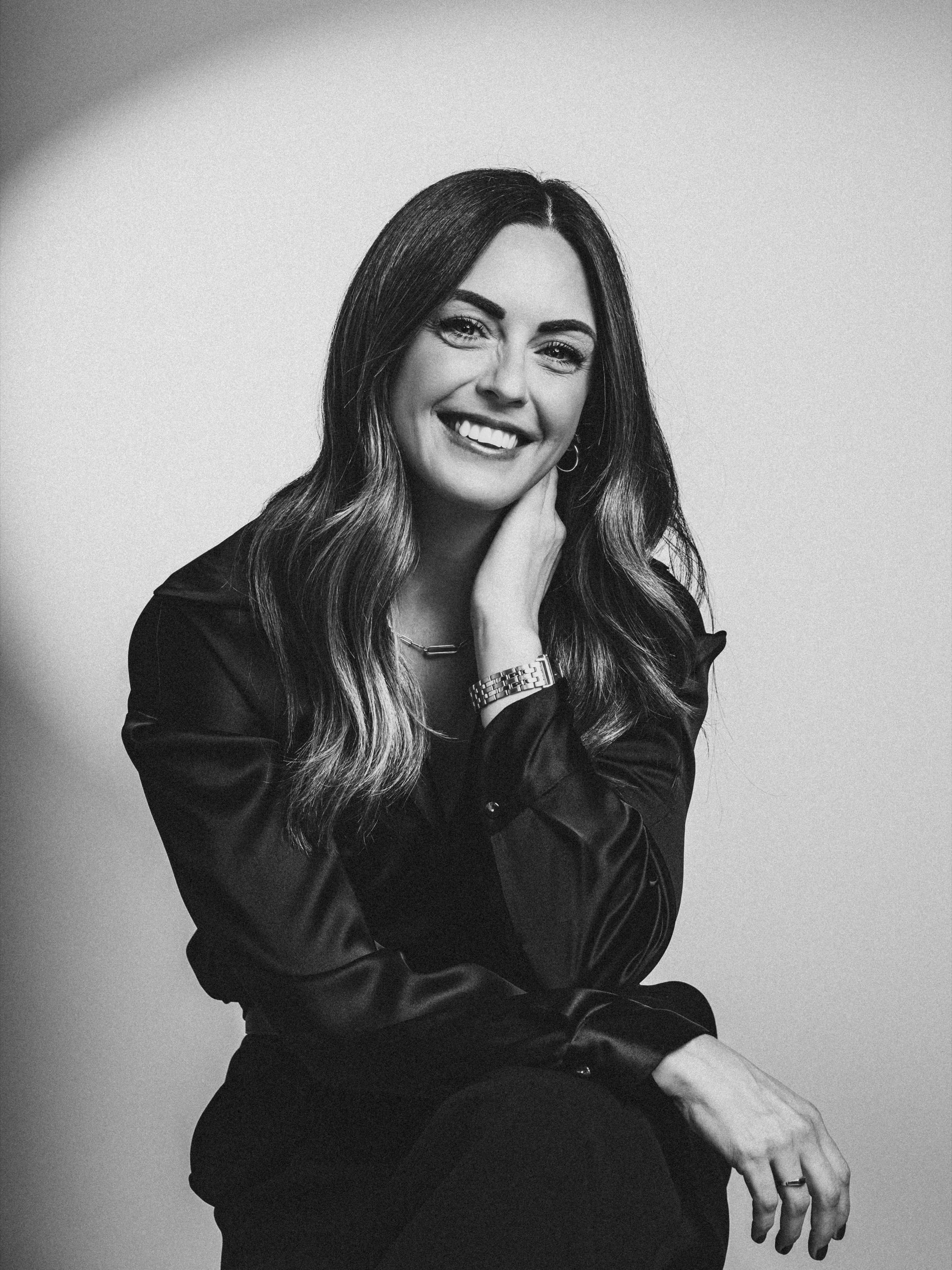 Black-and-white portrait of Sarah smiling with her hand at her neck.