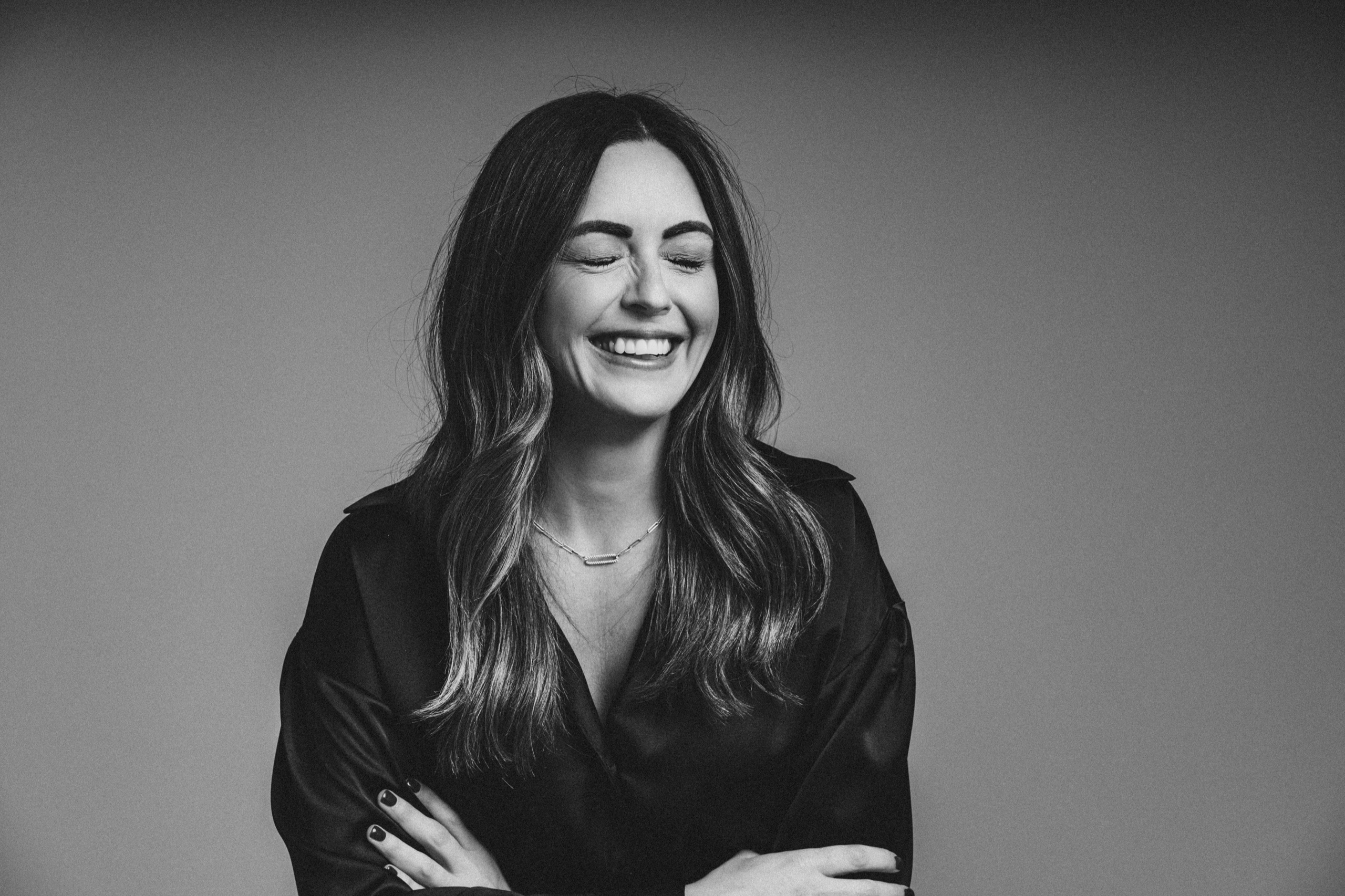 Sarah laughing with her eyes closed, in black and white.