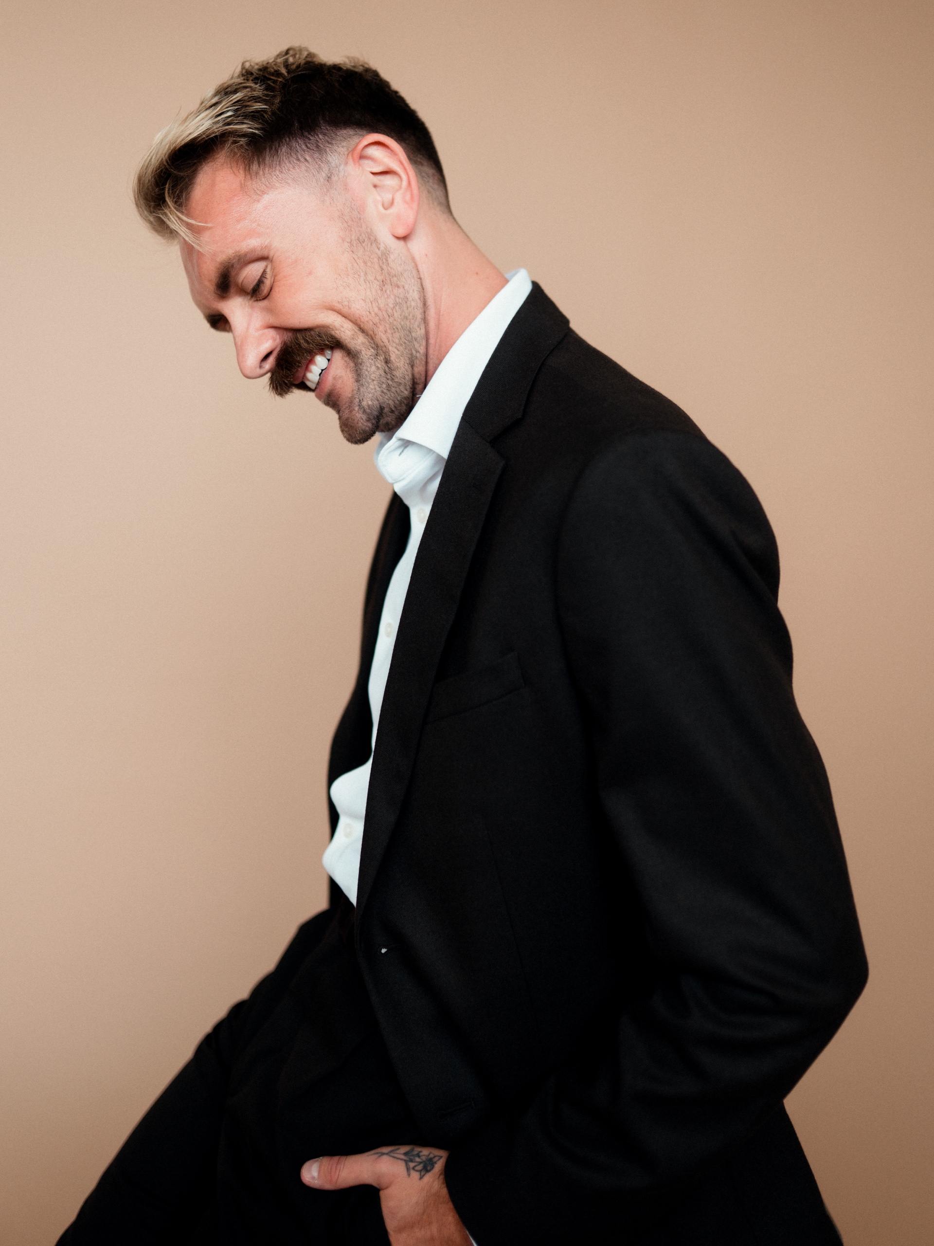 Jordon smiling and looking down in a black suit.