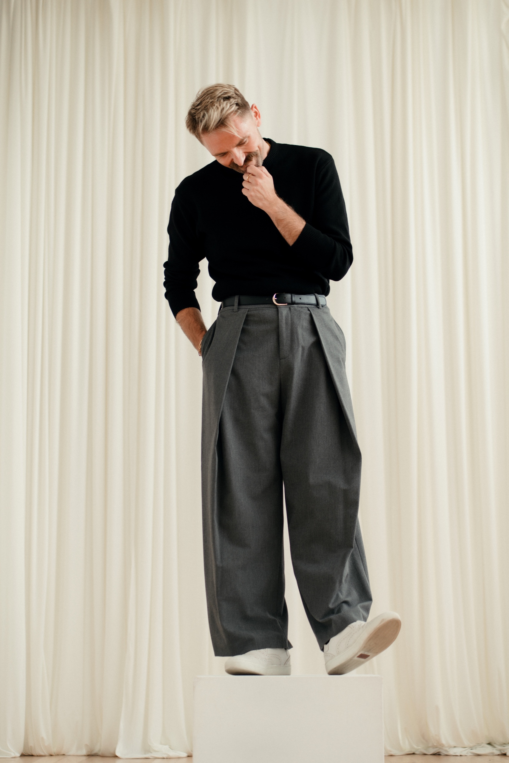 Jordon standing on a white plinth in grey trousers and white shoes.