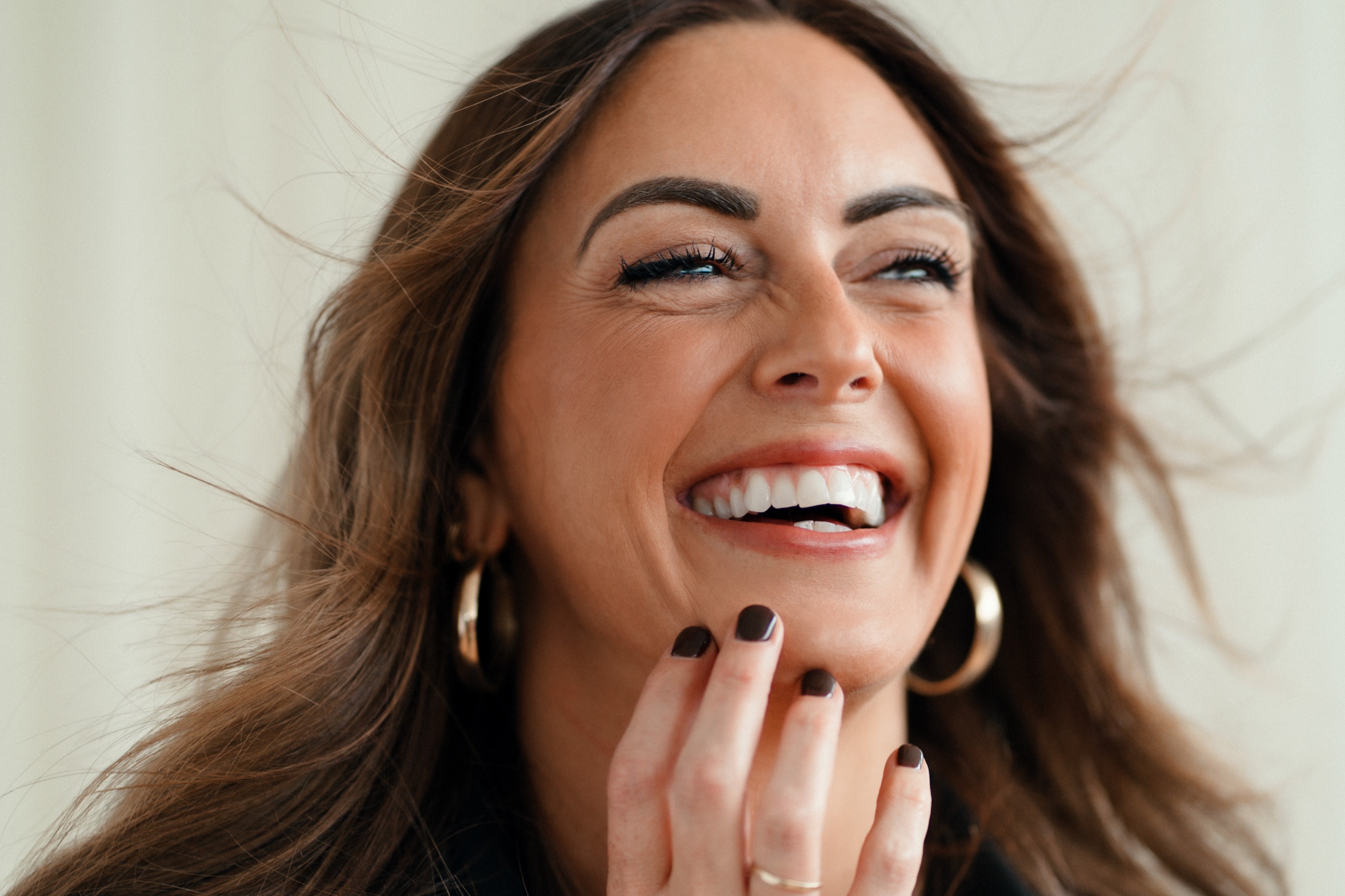 Close portrait of Sarah smiling with her hand near her chin.