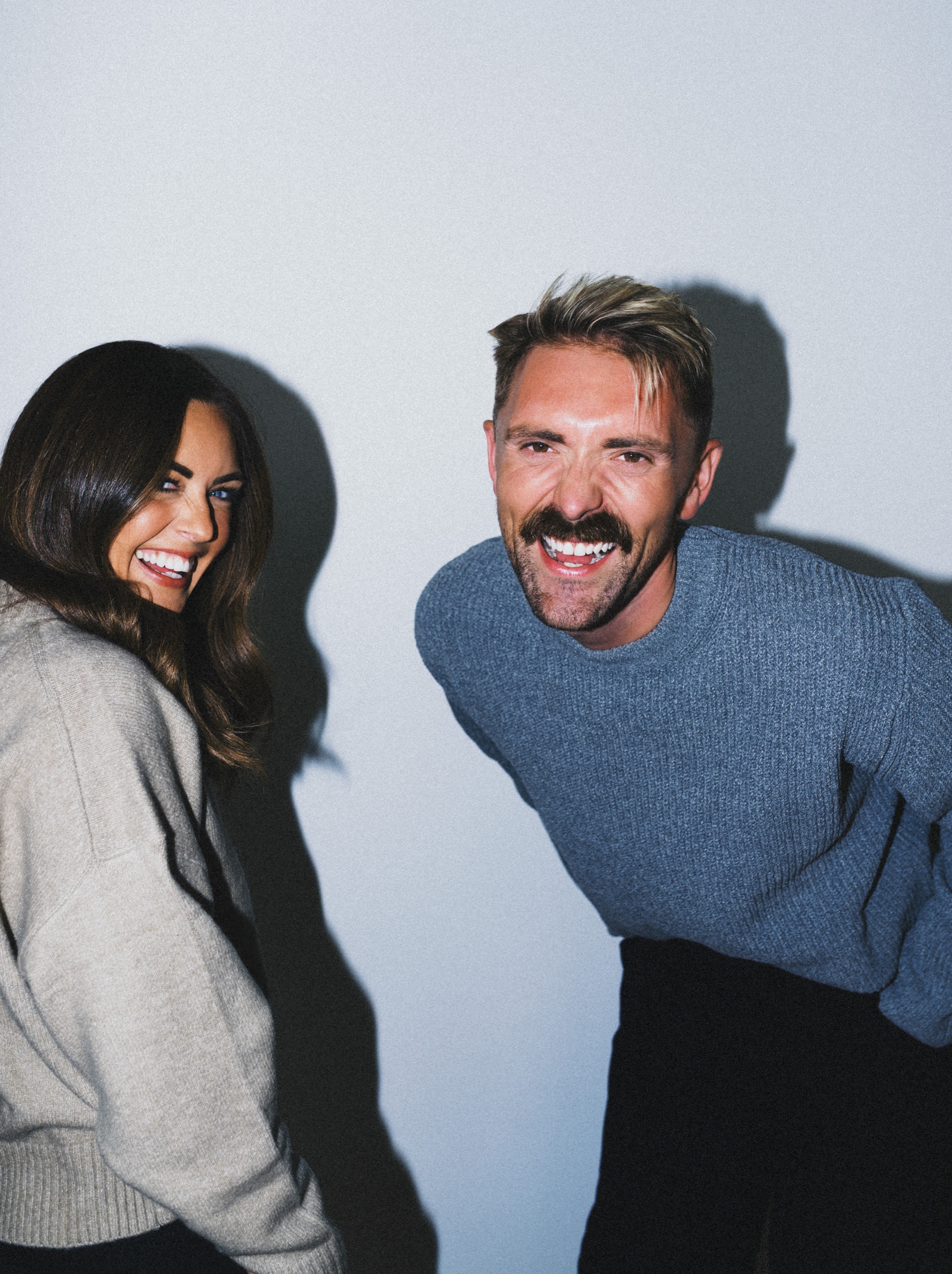 Jordon and Sarah smiling together in blue and neutral knitwear.