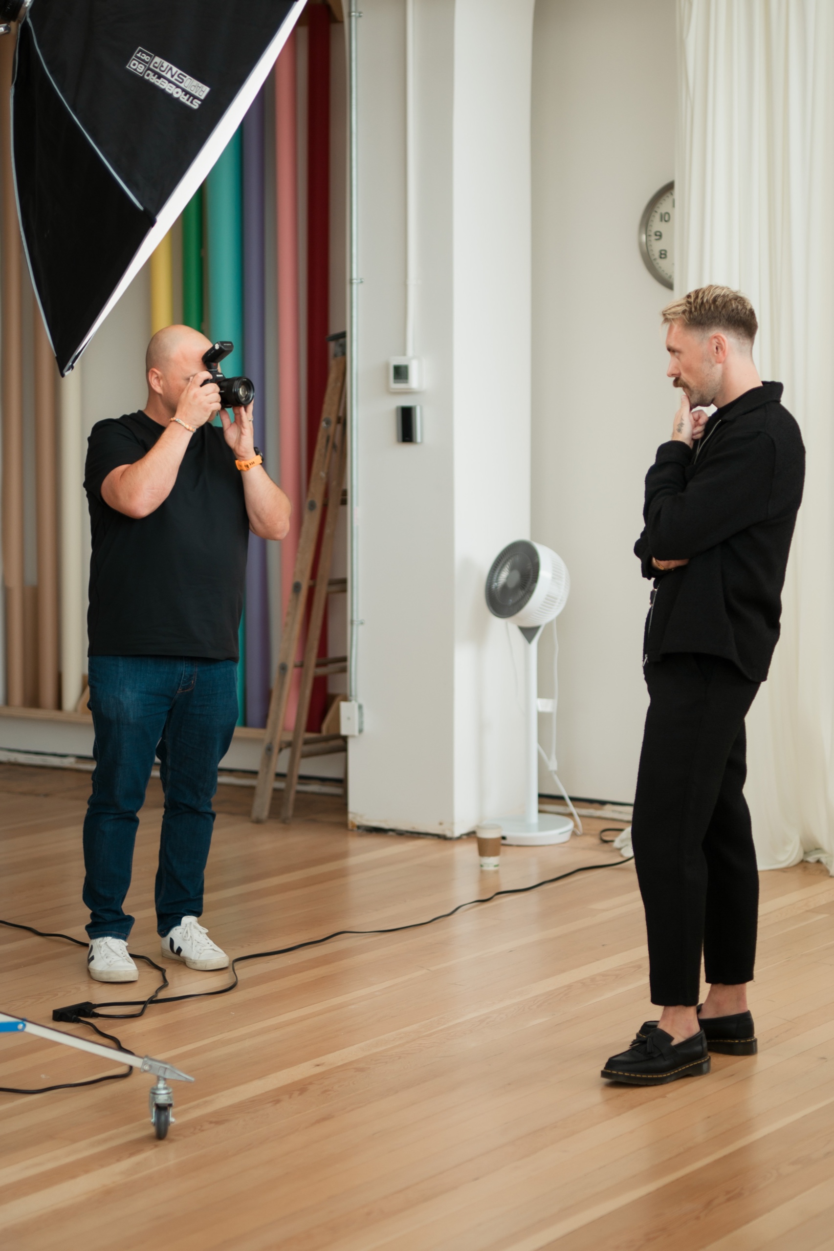 A photographer working with Jordon beside a studio softbox.